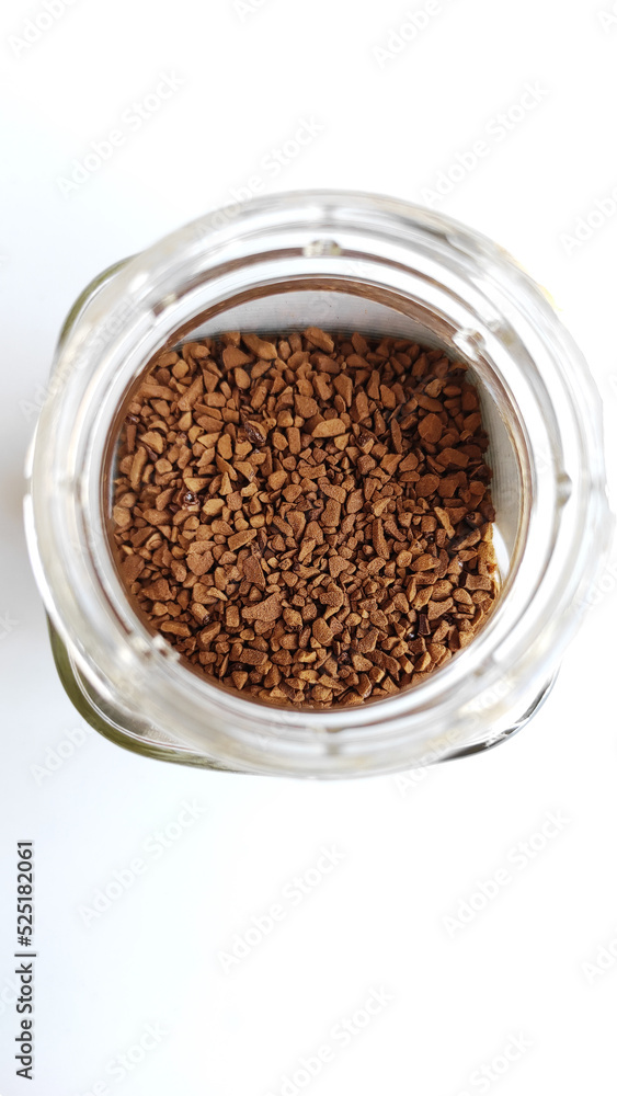 ISOLATED OPEN TRANSPARENT GLASS JAR OF INSTAT COFFEE ON WHITE TABLE, TOP VIEW, SELECTIVE FOCUS ISOLATED OPEN TRANSPARENT GLASS JAR OF INSTAT COFFEE ON WHITE TABLE, TOP VIEW, SELECTIVE FOCUS
