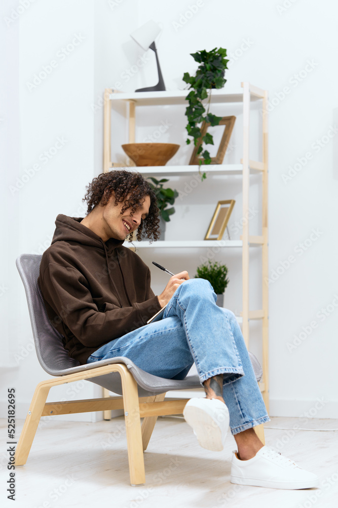 A young man sit on a chair with a notepad and a writing pen isolated background