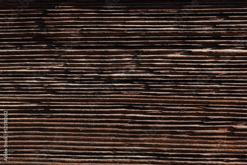 Old and weathered dark brown cracked wood beam surface with nice rough grain texture.