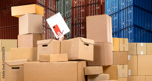 Warehouse box. Clipboard in hand. Cardboard boxes stocktake or accounting. Woman hand in heap boxes. Metaphor for confusion in warehouse accounting. Warehouse lot chaos. Working accounting. Art focus photo