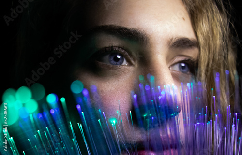 Female looks through futuristic teal coloured bokeh, millennial woman with advanced fiber optic technology, Christmas