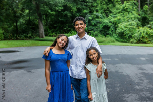 Photography Three siblings standing outside their home hugging and embracing for a picture