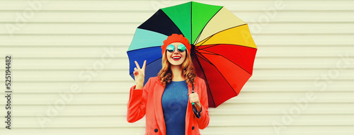 Autumn portrait of happy cheerful smiling young woman with colorful umbrella wearing red coat and beret on white background
