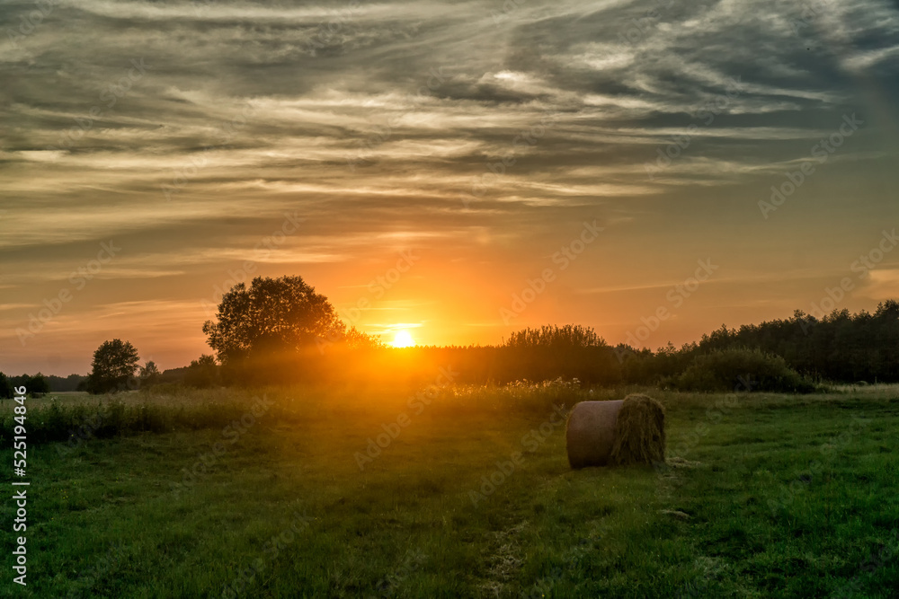 Sunset over the meadow with hay bale in summer. Landscape of Biebrza National Park in Poland, Europe. Dramatic clouds over the grassland. Sunset over the meadow with hay bale in summer. Landscape of Biebrza National Park in Poland, Europe. Dramatic clouds over the grassland.