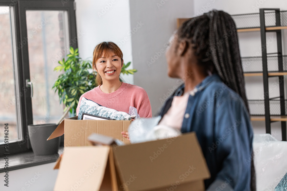 moving, people and real estate concept - happy smiling women with boxes at new home moving, people and real estate concept - happy smiling women with boxes at new home