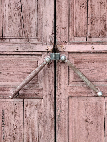 A padlock hangs on a closed door with handles of an ancient house