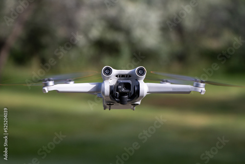 Close up drone with camera sensors and props flying in air with nature behind - DJI Mini 3 Pro aerial uav