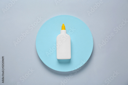 Bottle of glue on color background, top view