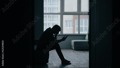Stressed caucasian middle-aged man sitting on the sofa in bedroom while get bad news from mobile phone. Depressed and hopeless male being alone with negative emotion.