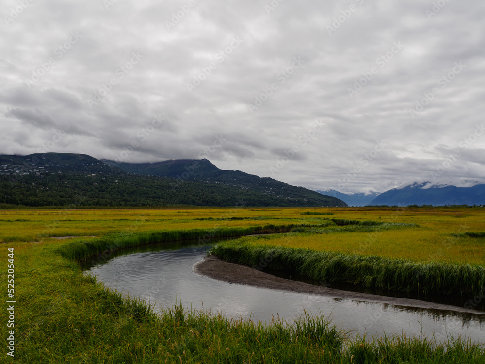 Winding River with Mountains and Clouds in the background