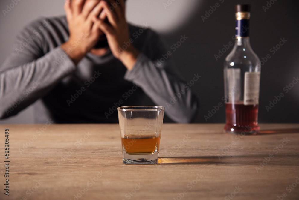 Bottle and glass of whisky and sad man Bottle and glass of whisky and sad man