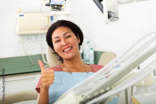 Portrait of smiling satisfied asian woman visiting dentist giving thumbs up