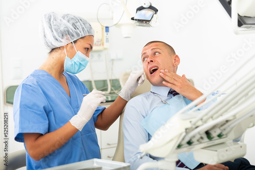 Male patient shows sick tooth to a dentist in a dental clinic