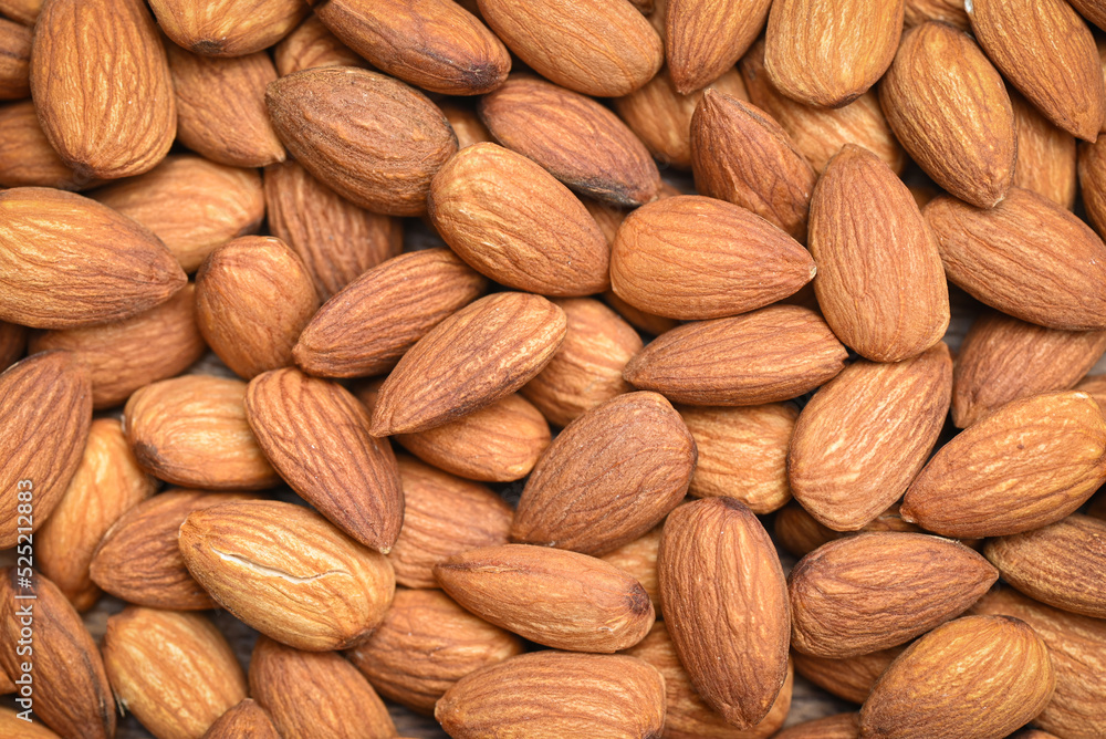 Fototapeta premium Almonds nuts on background, Close up delicious sweet almonds top view, roasted almond nut for healthy food and snack