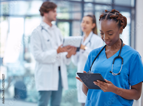 Female nurse or doctor browsing on a tablet for patient diagnosis or treatment on a medical or mobile healthcare app in a hospital. Professional gp or surgeon wearing scrubs while working in a clinic photo