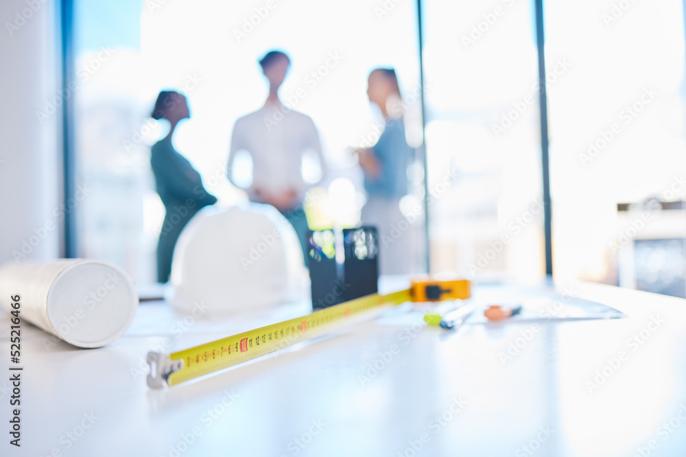 Fototapeta premium Creative engineering designer discuss building plans in a corporate business. Measure tape on a table or desk in an architecture company office with engineer employee consulting in the background