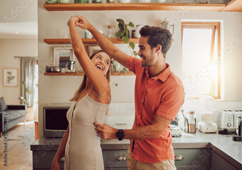 Joyful, dancing and loving couple bonding and having fun in the kitchen together at home. Energetic, fun and active relationship sharing a dance and romantic moment while enjoying their anniversary. photo