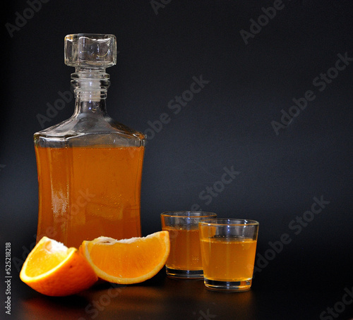 Obraz na płótnie Orange liqueur, strong homemade alcohol and pieces of ripe citrus fruits on a black background
