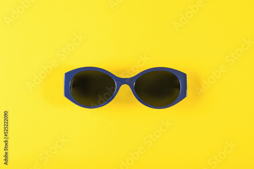 Stylish blue sunglasses on a yellow background.