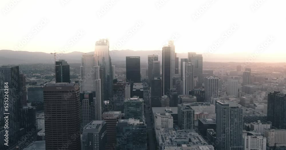 A young adult male stands on a skyscraper in Downtown Los Angeles at sunrise raising his hands as a drone zooms past. A young adult male stands on a skyscraper in Downtown Los Angeles at sunrise raising his hands as a drone zooms past.