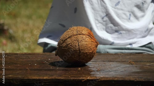 Slow motion of man chopping fresh organic coconut in half with machete.