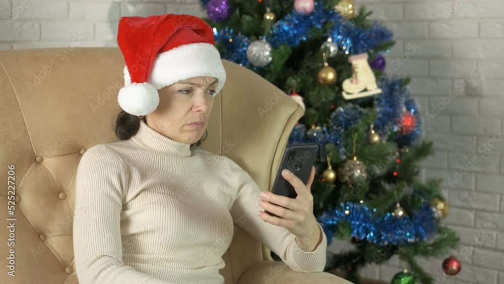 Sad news at Christmas eve. A woman in Santa hat read about sad new on her phone during New Year holidays. Sad news at Christmas eve. A woman in Santa hat read about sad new on her phone during New Year holidays.