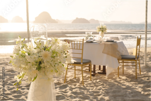 Beautiful table set up for a romantic dinner on the beach with flowers and candles. Catering for a romantic date, wedding or honeymoon background. Sunset beach dinner. selected focus.