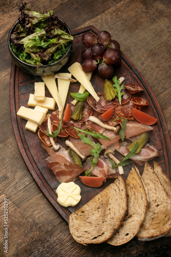 mixed cheese and cold cuts board on wood background