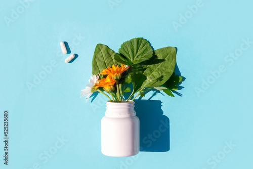 White pills and of bottle with herbal on blue background. Homeopathy, naturopathy, nutraceuticals and healthcare concept. Top view Flat lay photo