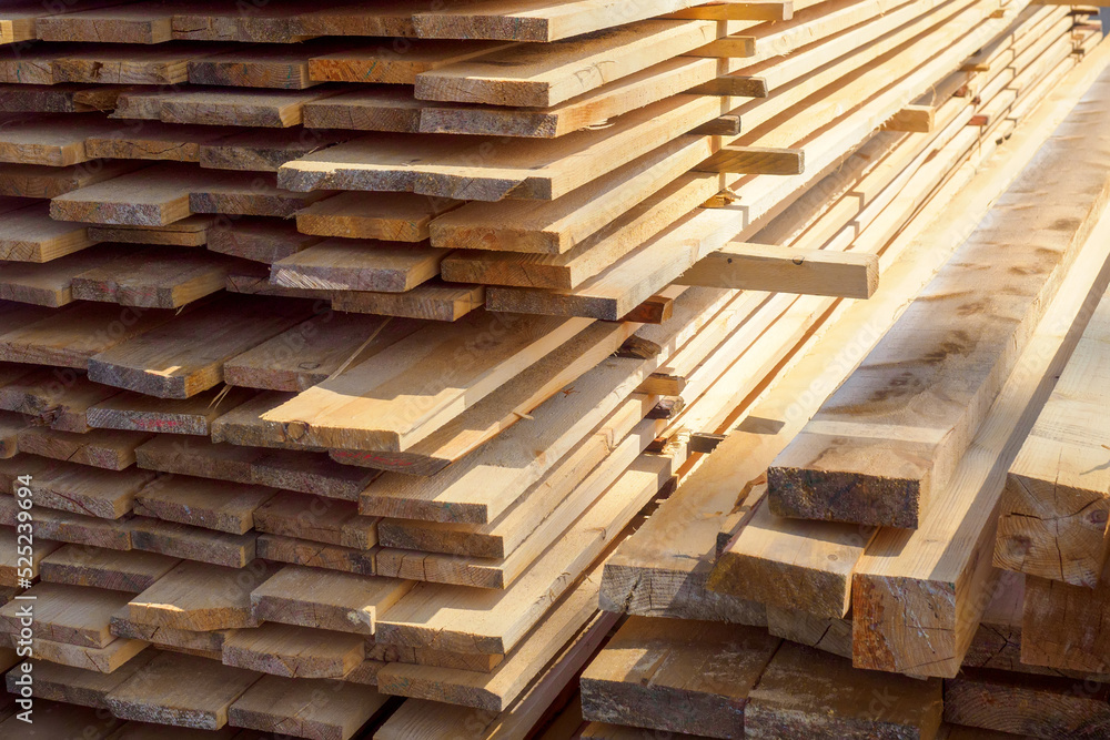 Fototapeta premium Wooden boards are stacked in a sawmill or carpentry shop. Sawing drying and marketing of wood. Industrial background