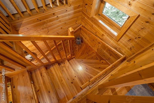 Upward view of wooden stairs and handrail in country house.