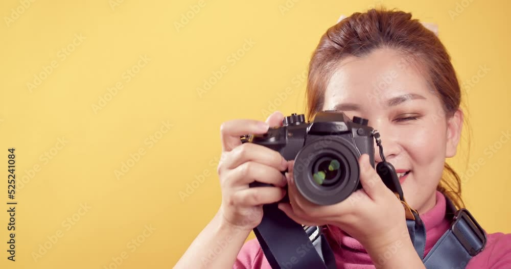 Asian gorgeous young woman in a studio shot over an isolated yellow background using a digital camera for travel and technology concept. Asian gorgeous young woman in a studio shot over an isolated yellow background using a digital camera for travel and technology concept.
