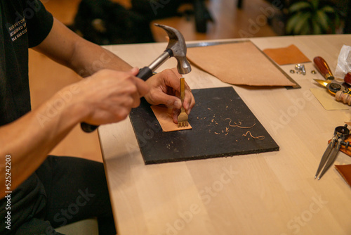 Craftsman hammers a leather piece 