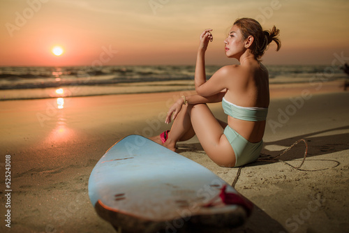 woman sitting beside surfboard on the beach on sunset,shilouete photo photo