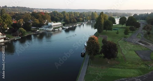 Peaceful sunrise drone shot of a single rower on the river in Henley-on-Thames, Oxfordshire. The clip starts far away from the rower, revealing the beautiful landscape, and slowly flys closer. photo