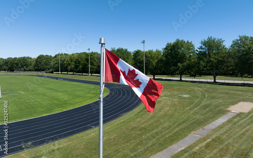 A waving Canadian flag is seen closeup at a residential track and field centre, seen on a sunny summers day.