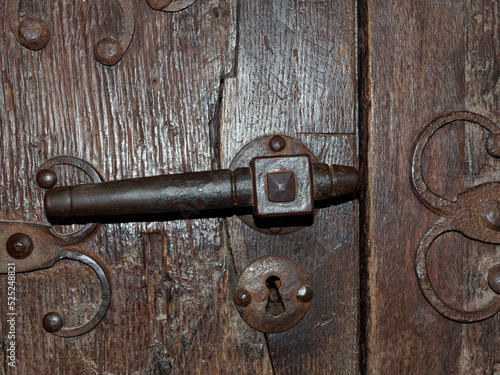 Old door handle, close-up of an old metal door handle on a solid brown wooden door.