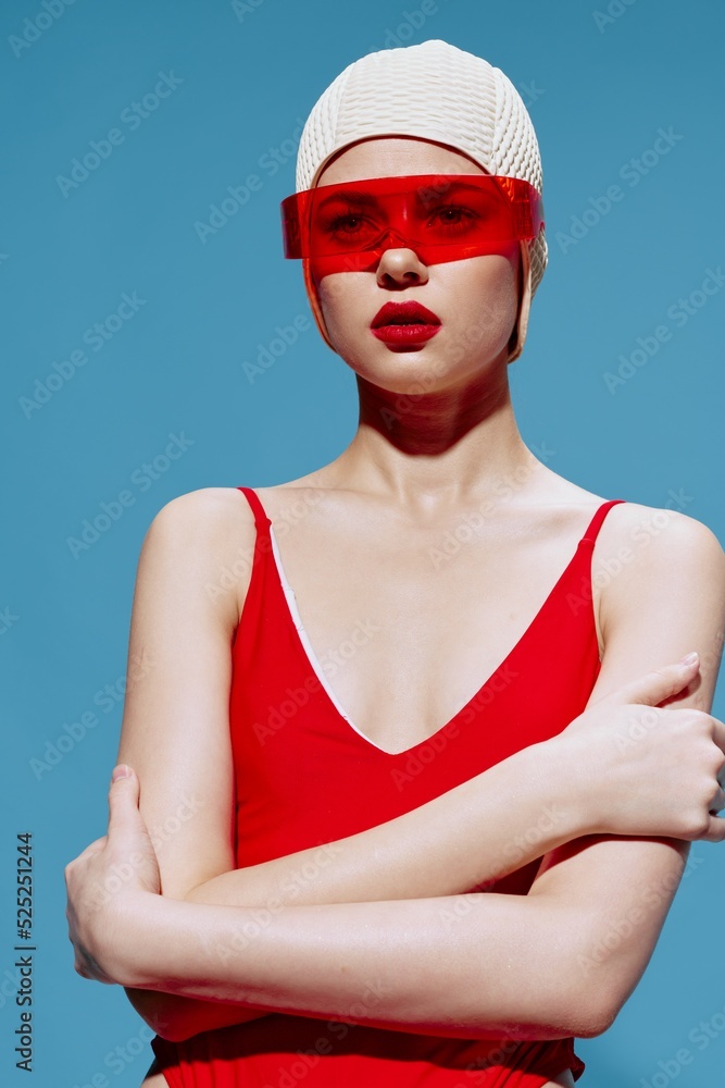 A swimmer in a red retro swimsuit and conceptual glasses hugs herself and looks forward A swimmer in a red retro swimsuit and conceptual glasses hugs herself and looks forward