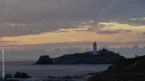 Leuchtturm auf Felseninsel im lila Sonnenuntergang