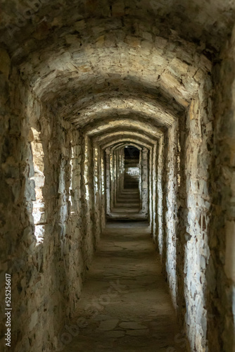 A long stone tunnel corridor with windows in an old castle. Selective focus. © Nataliia