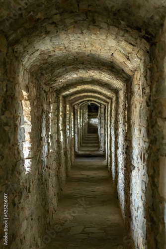 A long stone tunnel corridor with windows in an old castle. Selective focus.