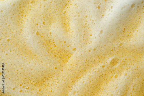 Foam on a yellow background. Soapy liquid, shower gel, shampoo swatches texture with bubbles. Natural sunshine and shadows. Skin care cleansing cosmetic in top view. Beauty concept for face and body