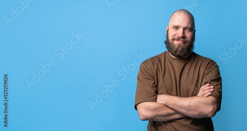 Bearded middle-aged white man in brown t-shirt over blue background. Mock up, template, copy space. Positive, handsome, smiling. photo