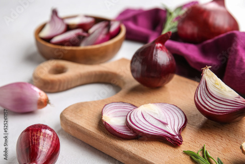 Wooden board with cut red onion on light background, closeup