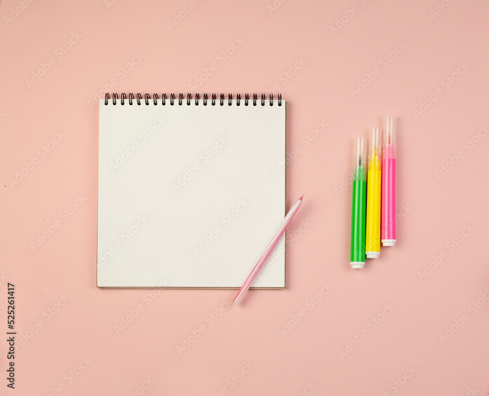 Notepad with white sheets and a pen and markers on a pink background Notepad with white sheets and a pen and markers on a pink background