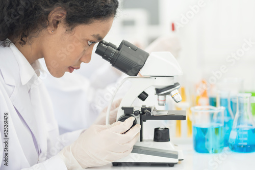 Close up woman scientist looking through microscope doing analysis for germs and bacteria of test sample in the laboratory. Female specialist working with biotechnology research with microscope