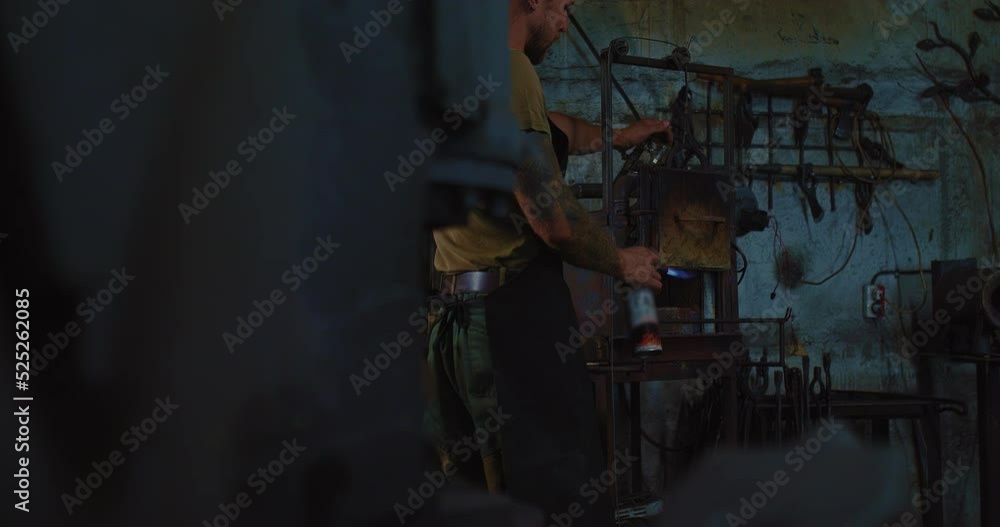 man is kindling blacksmith furnace in smith, young modern craftsman in workshop, 4K, Prores man is kindling blacksmith furnace in smith, young modern craftsman in workshop, 4K, Prores