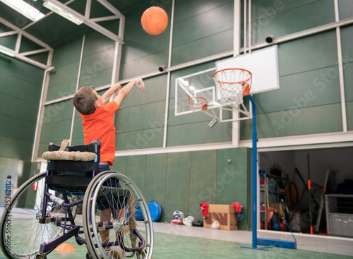 Boy in a wheelchair throwing the ball into the basketball basket © WORLDLIFEPHOTO