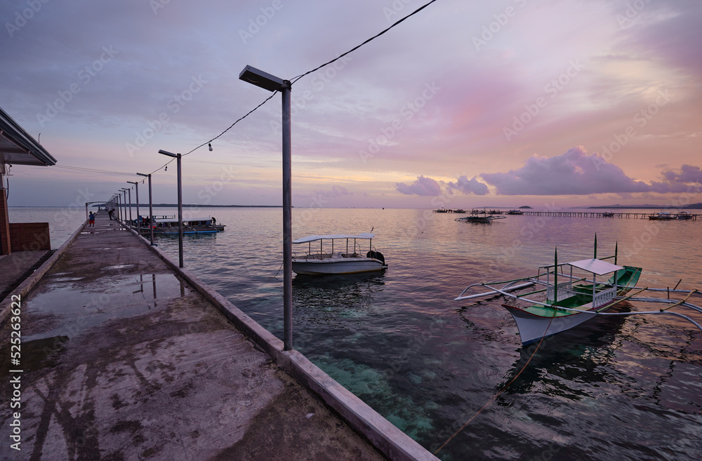 Beautiful colorful sunset on the seashore with fishing boats. Philippines, Siargao Island.