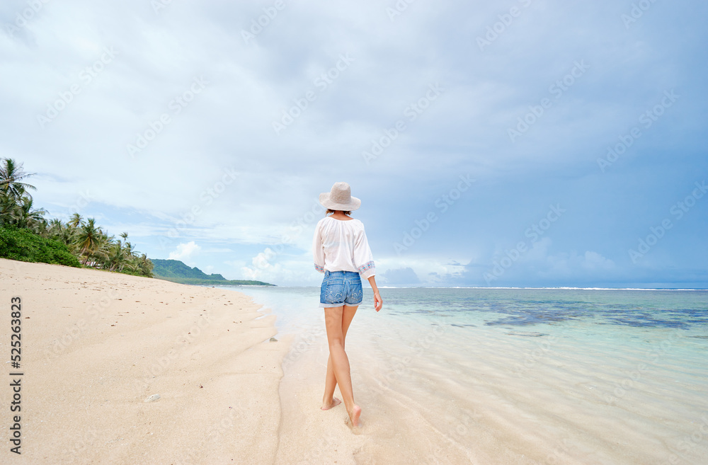 Vacation on the seashore. Back view of young woman walking away on the beautiful tropical white sand beach. Vacation on the seashore. Back view of young woman walking away on the beautiful tropical white sand beach.